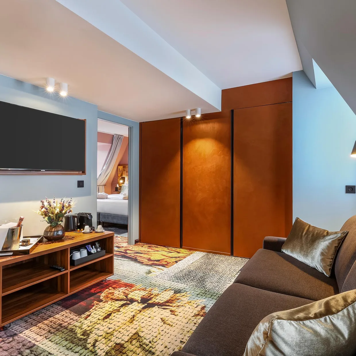 Salon d'hôtel avec canapé, table basse, télévision et porte ouverte sur la chambre à coucher