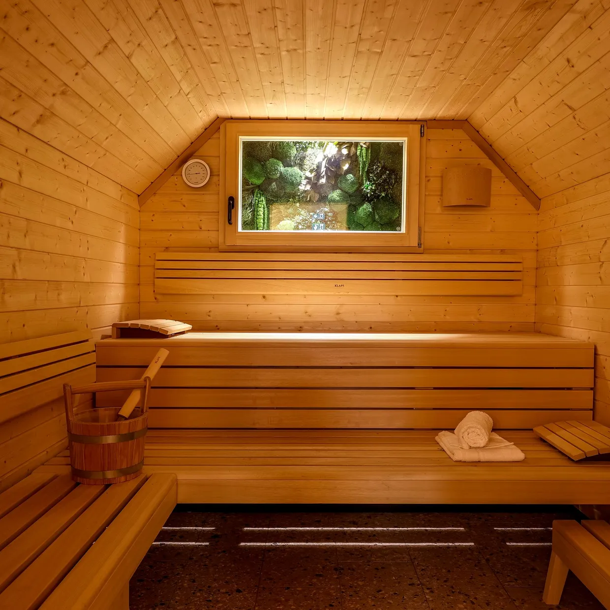 Salle en bois avec bancs, fenêtre et seau, éclairée par une lumière douce