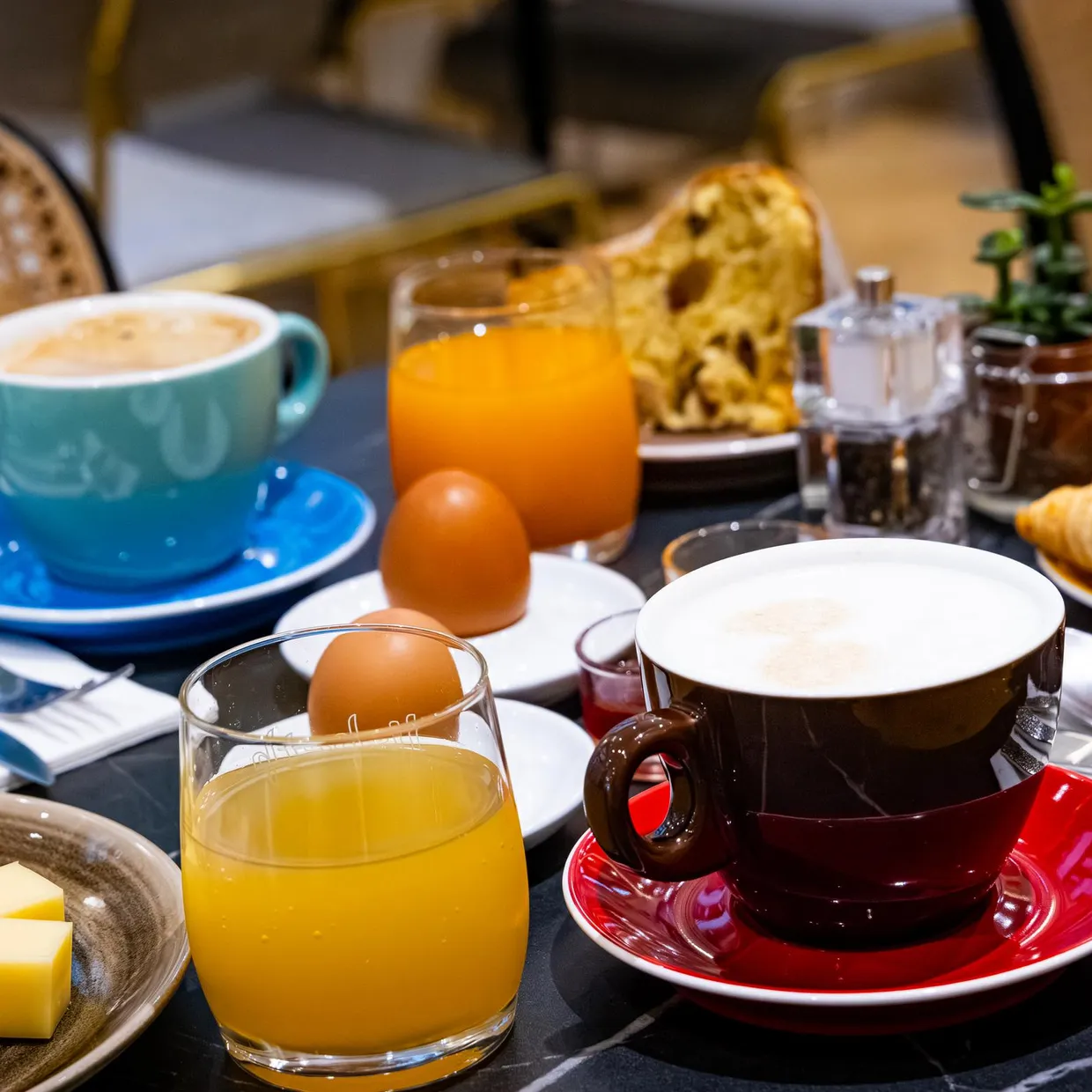 Table de petit-déjeuner avec café, jus d'orange, croissants, œufs, beurre, charcuterie et couverts