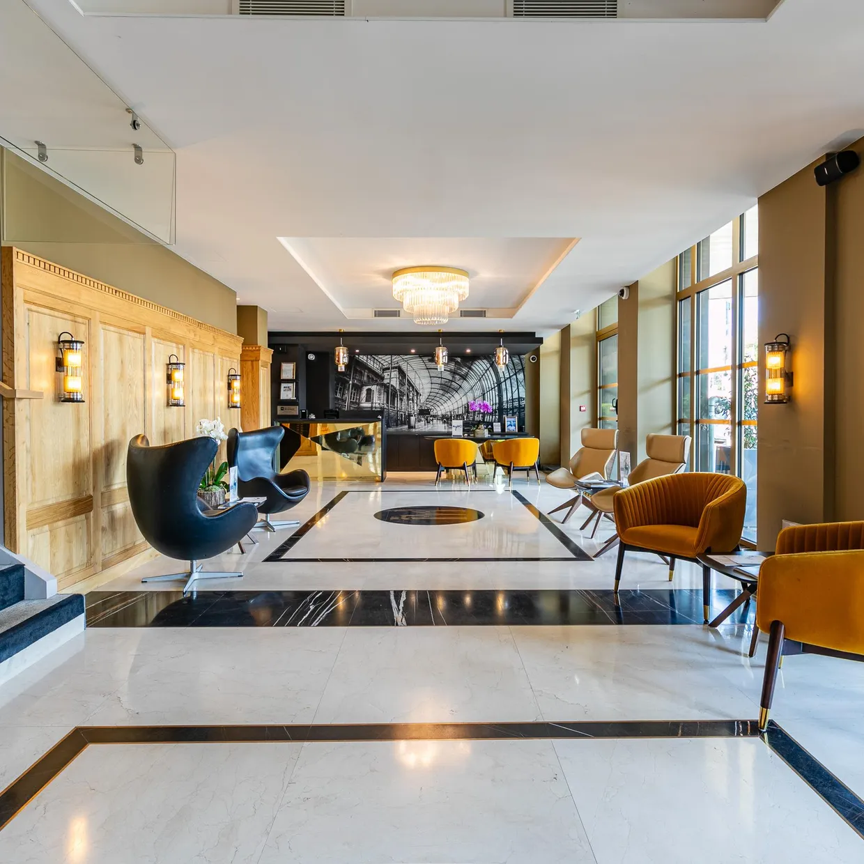 Lobby d'un hôtel avec des fauteuils, un escalier, un comptoir d'accueil et une décoration moderne