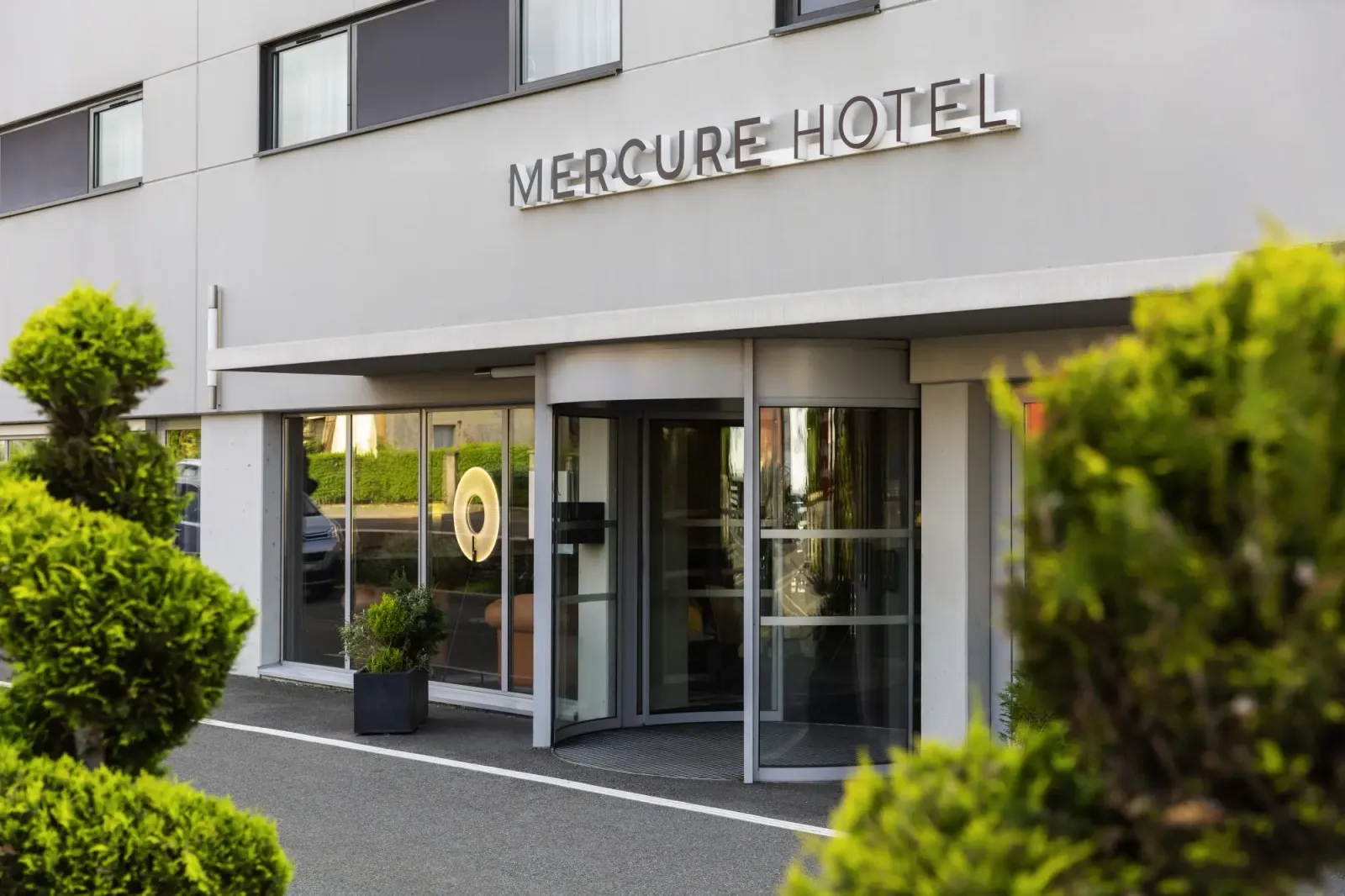 Entrée principale d'un hôtel Mercure avec des plantes vertes en premier plan