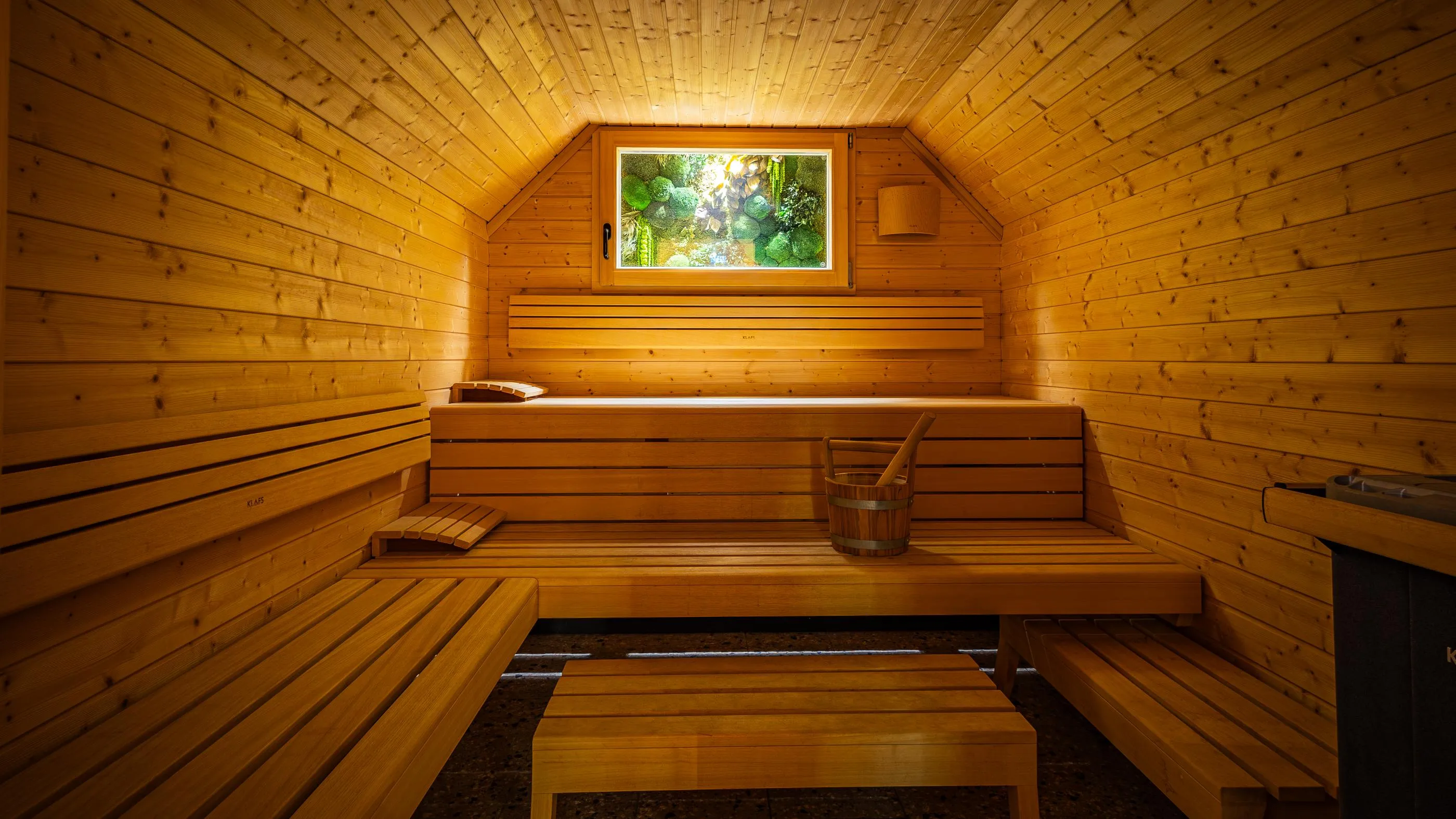 Salle en bois avec bancs et seau, fenêtre donnant sur un paysage extérieur