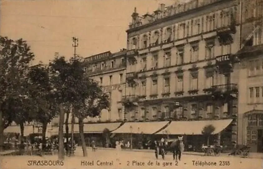 Vieille photographie en noir et blanc d'un bâtiment de plusieurs étages avec des balcons, des arbres et des passants devant, à Strasbourg, avec une enseigne "Hôtel Central" visible