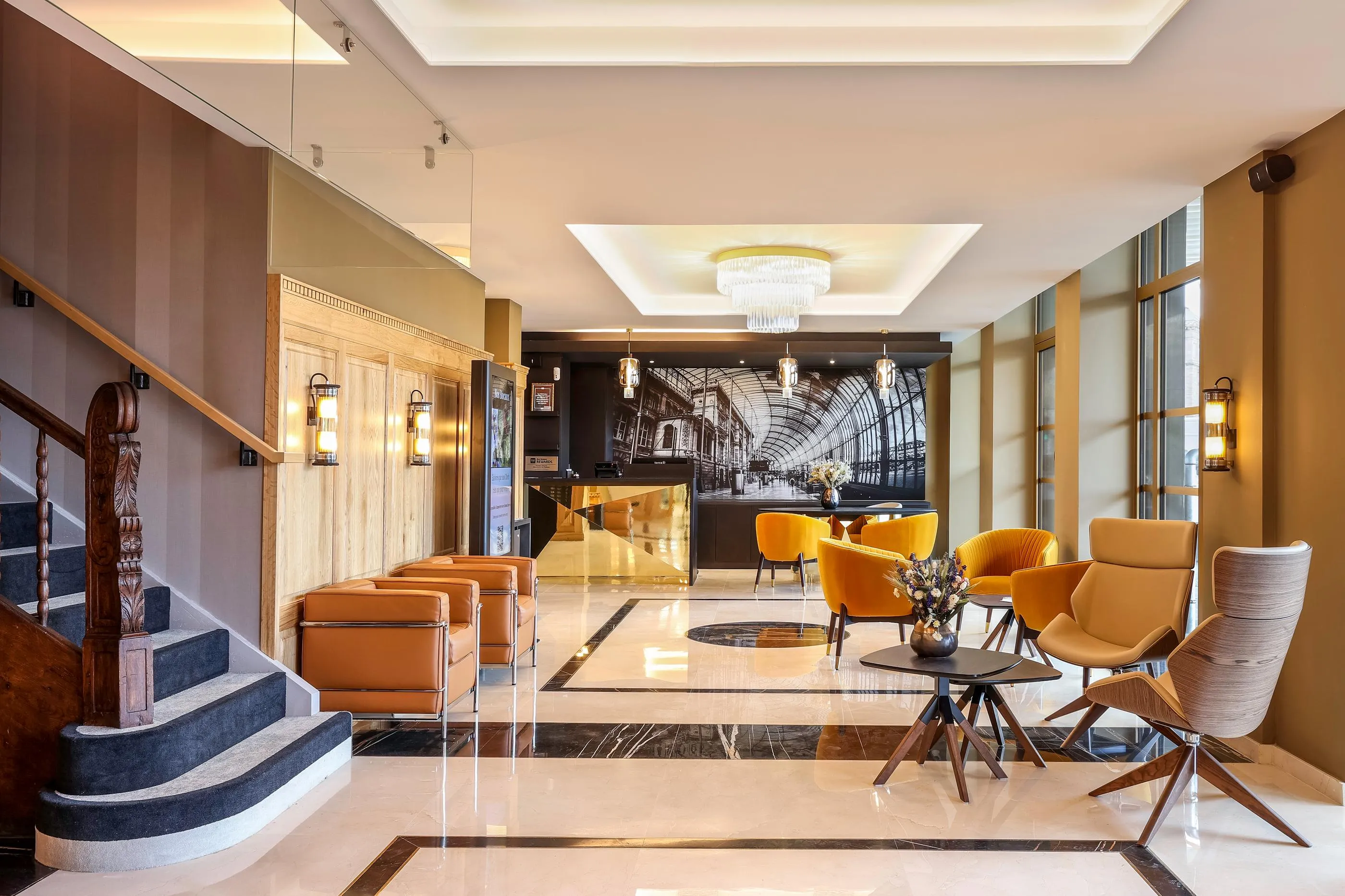 Lobby d'hôtel avec des canapés et des fauteuils, une réception et un escalier sur le côté