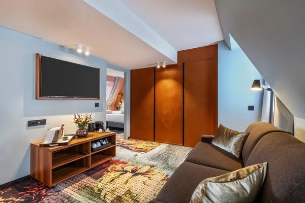Salon d'hôtel avec canapé, table basse, télévision et porte ouverte sur la chambre à coucher