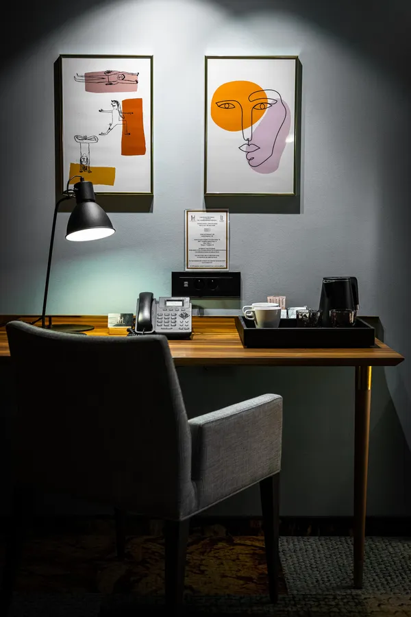 Bureau avec téléphone, lampadaire, deux chaises et deux tableaux abstraits accrochés au mur