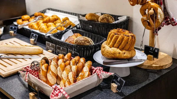 Assortiment de pains et viennoiseries présentés sur des plateaux et dans des paniers en osier avec des étiquettes