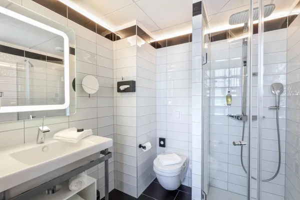 Salle de bain moderne avec lavabo, toilettes, douche et miroir éclairé
